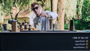 Profesionalni cocktail barman pripravlja koktajle na dogodku, ustvarja edinstveno izkušnjo za goste.