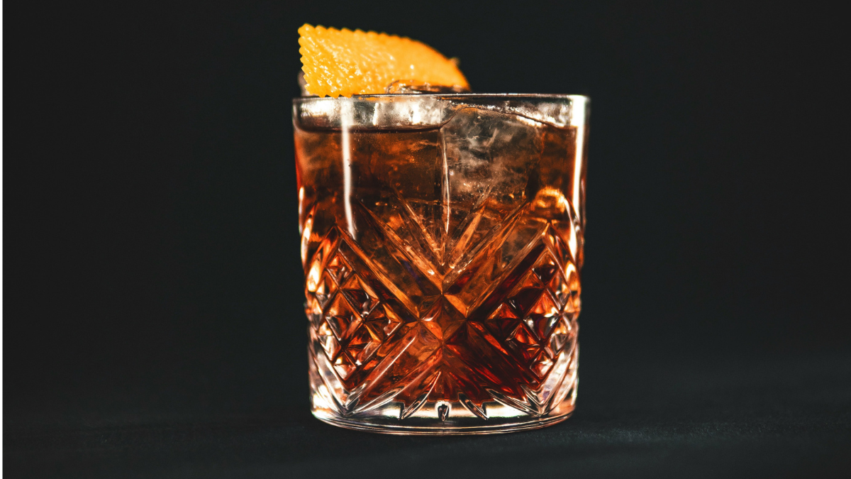 Klasični Negroni koktajl v kristalnem kozarcu s pomarančno lupinico